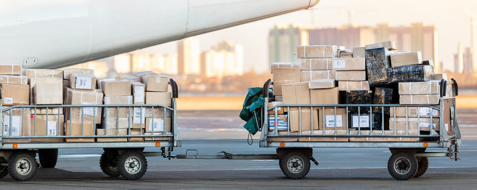 lose-up detail view of cargo cart trolley full with commercial parcels against turboprop cargo plane.